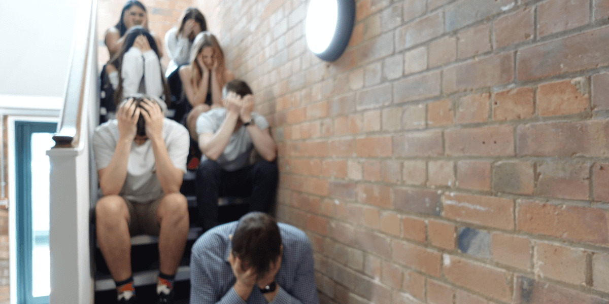 An image of our team, LoudLocal, sat on the stairs togethert, everyone having their heads in their hands and looking down.